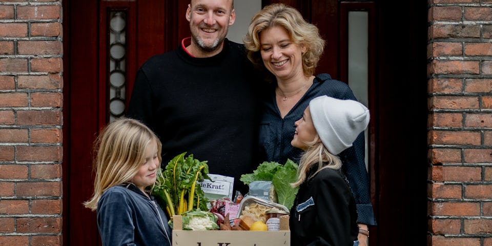 Een gezin met kinderen houden een maaltijdbox met lokale producten vast | Herfst-winter
