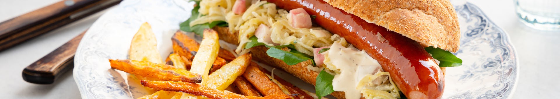 Broodje hotdog met zuurkoolsalade en groentefrietjes